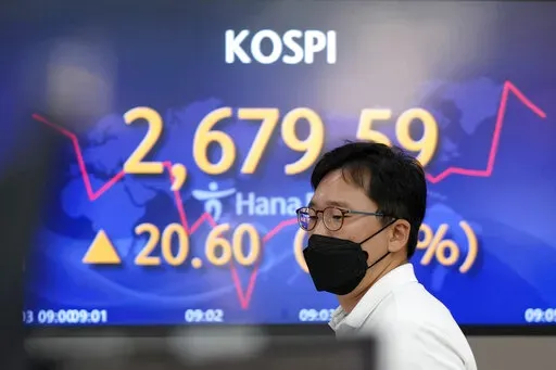 A currency trader walks by the screens showing the Korea Composite Stock Price Index (KOSPI) at a foreign exchange dealing room in Seoul, South Korea, Friday, June 3, 2022. Asian shares rose Friday amid mixed signs for investors such as rising energy prices and COVID-19 restrictions easing in China. (AP Photo/Lee Jin-man)