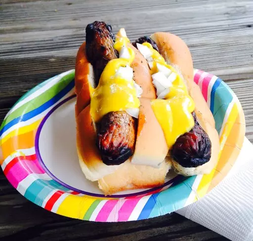 This 2015 photo shows yellow mustard on top of a pair of grilled hotdogs. Mustards are made around the world and with all kinds of ingredients besides mustard seeds. Try picking up local mustards when you travel. And use mustard on more than just sandwiches or hot dogs. Think about salad dressings and sauces and dips. (AP Photo/Carolyn Lessard)