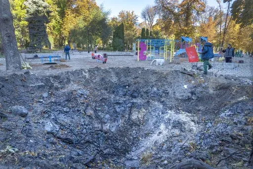 A man passes past a rocket crater at playground in city park in center Kyiv, Ukraine, Tuesday, Oct. 11, 2022.  On Friday, Oct. 14, The Associated Press reported on stories circulating online incorrectly claiming Ukrainian media is reporting that President Volodymyr Zelenskyy’s office was destroyed by a missile strike.  (AP Photo/Efrem Lukatsky)