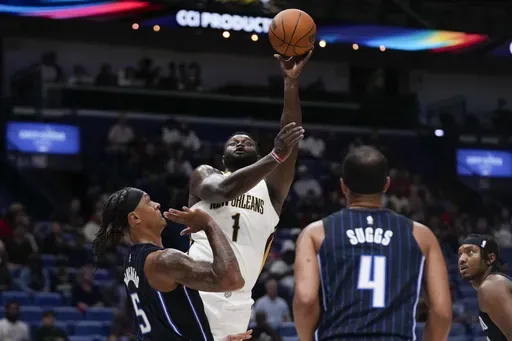 New Orleans Pelicans forward Zion Williamson (1) shoots over Orlando Magic forward Paolo Banchero (5) and guard Jalen Suggs (4) in the first half of an NBA preseason basketball game in New Orleans, Monday, Oct. 7, 2024. (AP Photo/Gerald Herbert)