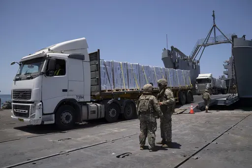 U.S. Army soldiers stand next to trucks arriving loaded with humanitarian aid at the U.S.-built floating pier Trident before reaching the beach on the coast of the Gaza Strip, June 25, 2024. (AP Photo/Leo Correa, File)
