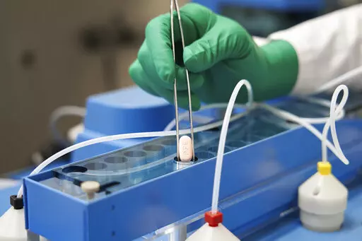 In this photo provided by Pfizer, a technician handles one of the company's COVID-19 Paxlovid pills. COVID-19 patients have two new treatment options that can be taken at home. But that convenience comes with a catch: The pills have to be taken as soon as possible once symptoms appear. U.S. regulators authorized the pills from Pfizer and Merck late 2021. (Pfizer via AP, File)