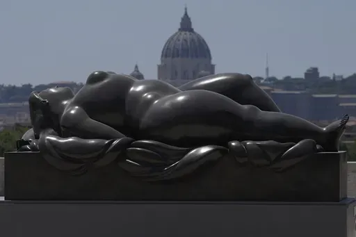 Botero's "Sleeping Venus" sculpture, installed in Rome's Pincio Terrace, Friday, July 19, 2024, appears to be in front of St. Peter's Basilica at The Vatican. Rome's storied streets and piazzas have become a vibrant canvas for Fernando Botero's exuberant sculptures, turning the city into an open-air museum of voluminous forms and daring artistry. (AP Photo/Gregorio Borgia)