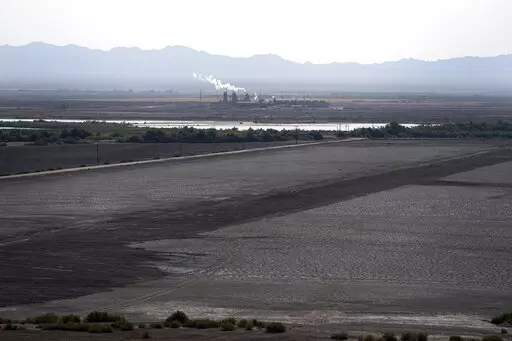 A dried up portion of the Salton Sea stretches out with a geothermal power plant in the distance in Niland, Calif., Thursday, July 15, 2021. Demand for electric vehicles has shifted investments into high gear to extract lithium from geothermal wastewater around the rapidly shrinking body of water. The ultralight metal is critical to rechargeable batteries. (AP Photo/Marcio Jose Sanchez, File)
