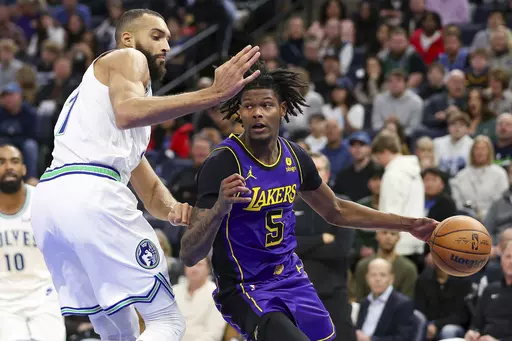 Los Angeles Lakers forward Cam Reddish (5) drives against Minnesota Timberwolves center Rudy Gobert (27) during the second half of an NBA basketball game Saturday, Dec. 30, 2023, in Minneapolis. (AP Photo/Matt Krohn)