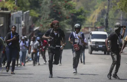 Journalists run for cover as protesters throw stones at a police car during a demonstration in Port-au-Prince, Haiti, March 19, 2025. (AP Photo/Odelyn Joseph, File)
