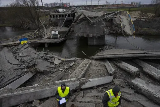 Engineers inspect the state of destruction of the bridge that connects Kyiv with Irpin, Ukraine, Wednesday, April 13, 2022. (AP Photo/Rodrigo Abd)