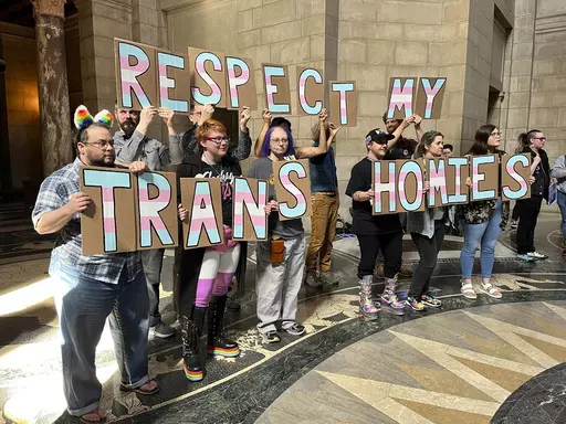 A group of around 200 people who turned out for a rally inside the Nebraska State Capitol hold up signs in support of the transgender community, Friday, March 24, 2023 in Lincoln, Neb. The rally was held to protest the advancement of a bill Thursday that would ban gender-affirming care for minors, as well as a bill that would criminalize allowing minors to attend drag shows. (AP Photo/Margery Beck)