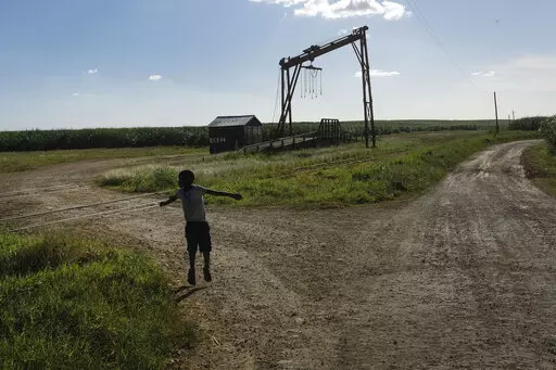 A youth plays near the machine where the sugar cane is weighed in the Lima batey, or neighborhood, in La Romana, where Central Romana Corporation, Ltd. operates its sugar operations in Dominican Republic, Nov. 17, 2021. The U.S. government announced Nov. 23, 2022 that it will detain all imports of sugar and related products made in the Dominican Republic by Central Romana Corporation, Ltd. amid allegations that it uses forced labor. (AP Photo/Matias Delacroix, File)
