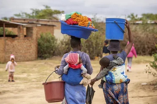 Women, with children on their backs carry out chores in Epworth, Zimbabwe, Thursday, Nov. 14, 2024. (AP Photo/Aaron Ufumeli)