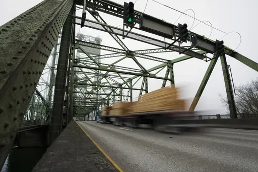 A logging truck drives on the Interstate 5 bridge that spans the Columbia River and connects Portland, Ore., with southwest Washington state, Feb. 13, 2024. Dozens of aging bridges, including this Interstate 5 bridge, in 16 states will be replaced or improved with the aid $5 billion of federal grants announced Wednesday, July 17, by President Joe Biden's administration as the latest beneficiaries of a massive infrastructure law. (AP Photo/Jenny Kane, File)