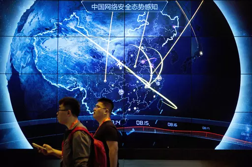 Attendees walk past an electronic display showing recent cyberattacks in China at the China Internet Security Conference in Beijing, on Sept. 12, 2017. Hackers linked to China were likely behind the exploitation of a software security hole in cybersecurity firm Barracuda Networks’ email security feature that affected public and private organizations globally, according to an investigation by security firm Mandiant. (AP Photo/Mark Schiefelbein, File)