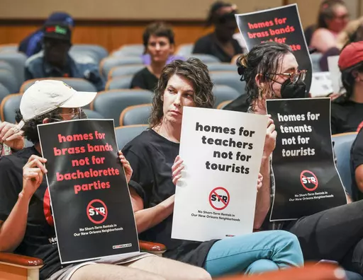 Residents against short term rentals sit in the front row with signs during a City Council meeting at City Hall in New Orleans, Thursday, March 23, 2023. (Sophia Germer/The Times-Picayune/The New Orleans Advocate via AP)