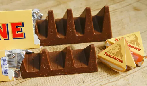 Two bars of the Toblerone Swiss chocolate are shown, at front is the new style 150 gram bar showing the reduction in triangular pieces, in the background is the older style 360 gram bar, pictured in London, on Nov. 8, 2016. The makers of Toblerone are stripping images of Switzerland's famed Matterhorn and the Swiss flag from the packaging of the milk-chocolate treat to comply with “Swissness” legislation, largely because some of its production is being outsourced to Slovakia. Mondelez Intern