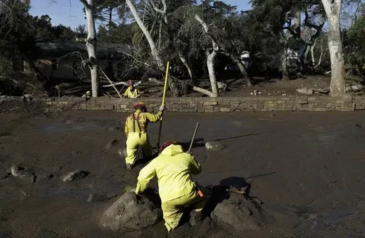 A Cal Fire search and rescue crew walks through mud near homes damaged by storms in Montecito, Calif., Jan. 12, 2018. (AP Photo/Marcio Jose Sanchez, File)