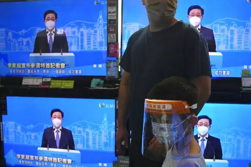 The TV screens show former Hong Kong Chief Secretary John Lee speaks during an online press conference to announce his candidacy for the Election of the Hong Kong chief executive, in Hong Kong, Saturday, April 9, 2022. (AP Photo/Kin Cheung)