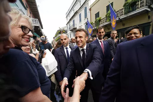 French President Emmanuel Macron greets the crowd as he walks down Royal Street in the French Quarter of New Orleans, Friday, Dec. 2, 2022. (AP Photo/Gerald Herbert)