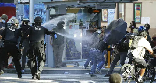 In this July 25, 2020, file photo, police pepper spray protesters, near Seattle Central College in Seattle, during a march and protest in support of Black Lives Matter.    Democratic lawmakers in California, Maryland and Washington passed far-reaching policing reforms this year in response to the 2020 killing of George Floyd in Minnesota. But the first full year of state legislative sessions since the killing sparked a summer of racial justice protests produced a far more mixed response in the r