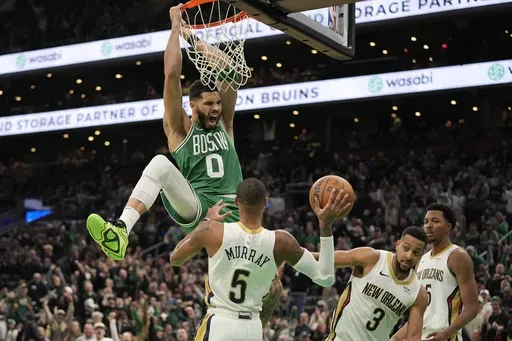 Boston Celtics' Jayson Tatum (0) screams after dunking on New Orleans Pelicans' Dejounte Murray (5), CJ McCollum (3) and Trey Murphy III (25) during the second half of an NBA basketball game, Sunday, Jan. 12, 2025, in Boston. (AP Photo/Robert F. Bukaty)