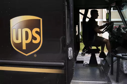 United Parcel Service driver Hudson de Almeida steers through a neighborhood while delivering packages, Friday, June 30, 2023, in Haverhill, Mass. UPS has reached a contract agreement with its 340,000-person strong union Tuesday, July 25, averting a strike that had the potential to disrupt logistics nationwide for businesses and households alike. (AP Photo/Charles Krupa, File)