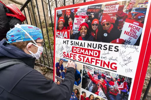 Zach Clapp, a nurse in the Pediatric Cardiac ICU at Mount Sinai Hospital signs a board demanding safe staffing during a rally by NYSNA nurses from NY Presbyterian and Mount Sinai, Tuesday, March 16, 2021, in New York. Negotiations to keep 10,000 New York City nurses from walking off the job headed Friday, Jna. 6, 2023, into a final weekend as some major hospitals braced for a potential strike by sending ambulances elsewhere and transferring such patients as vulnerable newborns. (AP Photo/Mary Al