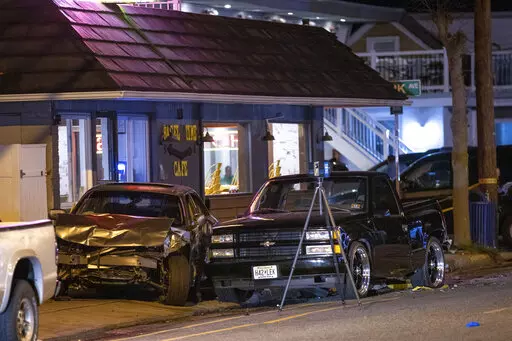 A sedan is wedged between a small, black pickup truck and the Bagel Time Cafe in Wildwood, N.J., early Sunday, Sept. 25, 2022. Authorities say at least two people were killed amid multiple crashes at a pop-up car rally. (Dave Hernandez/NJ Advance Media via AP)
