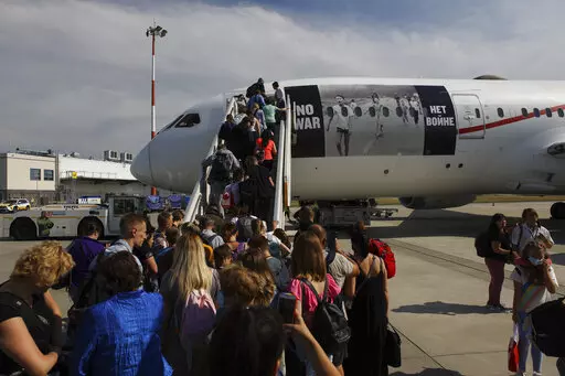 Ukrainian refugees board a plane before flying to Canada, from Frederic Chopin Airport in Warsaw, Poland, Monday, July 4, 2022. Phan Thị Kim Phuc, the girl in the famous 1972 Vietnam napalm attack photo, on Monday escorted 236 refugees from the war in Ukraine on a flight from Warsaw to Canada. Phuc’s iconic Associated Press photo in which she runs with her napalm-scalded body exposed, was etched on the private NGO plane that is flying the refugees to the city of Regina. (AP Photo/Michal Dyju