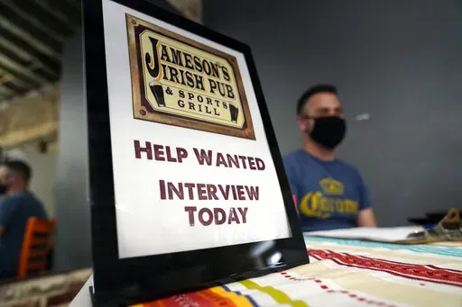 A hiring sign is shown at a booth for Jameson's Irish Pub during a job fair on Sept. 22, 2021, in the West Hollywood section of Los Angeles. California's unemployment rate has fallen to 5.4% after employers added a surprising 138,100 jobs in February. (AP Photo/Marcio Jose Sanchez, File)