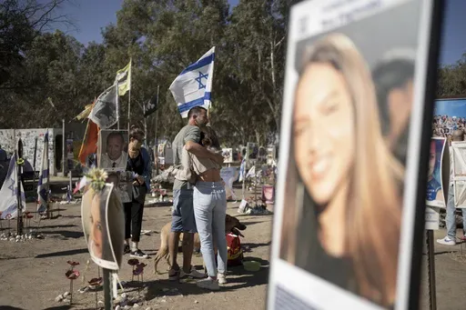 A family visits the the memorial marker of their loved one, Bar Lior Nakmuli, at the site of the Nova music festival, where hundreds of revelers were killed or kidnapped by Hamas, on the Jewish holiday of Simchat Torah, marking one year in the Hebrew calendar since the attack, near Kibbutz Re'im, southern Israel near the Gaza Strip, Thursday, Oct. 24, 2024. (AP Photo/Maya Alleruzzo)