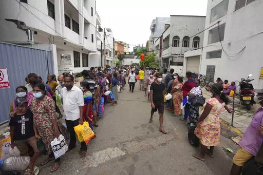 Sri Lankans queue up near a fuel station to buy kerosene in Colombo, Sri Lanka, Tuesday, April 12, 2022. When the Federal Reserve raises interest rates -- as it did Wednesday, May 4, 2022 -- the impact doesn’t stop with U.S. homebuyers paying more for mortgages or Main Street business owners facing costlier bank loans. The fallout can be felt beyond America’s borders, hitting shopkeepers in Sri Lanka, farmers in Mozambique and families in poorer countries around the world. (AP Photo/Eranga J