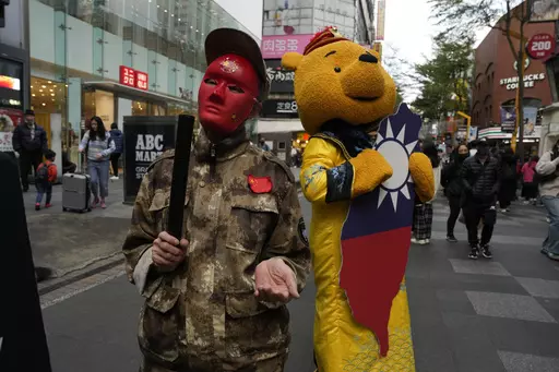 Protesters against the Chinese Communist Party dress up to depict authoritarian China and Winnie the Pooh representing Chinese President Xi Jinping, dressed as an emperor, and holding a Taiwan island cardboard cutout colored with the Taiwan flag in Taipei, Taiwan, Sunday, Jan. 7, 2024. Using military threats, diplomatic pressure, fake news and financial inducements for politicians, China is deploying a broad strategy to influence voters in Taiwan’s elections to pick candidates who favor unific
