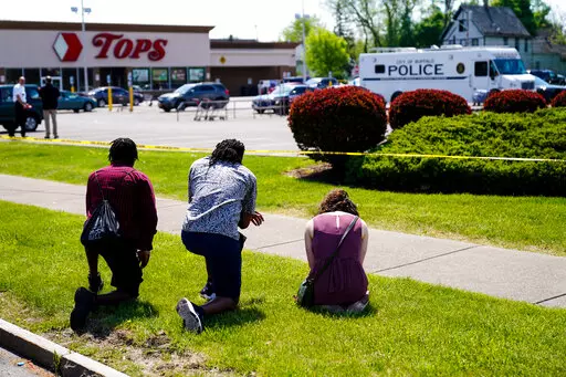 People pray outside the scene of Saturday's shooting at a supermarket, in Buffalo, N.Y., Sunday, May 15, 2022. The shooting is the latest example of something that's been part of U.S. history since the beginning: targeted racial violence. (AP Photo/Matt Rourke)