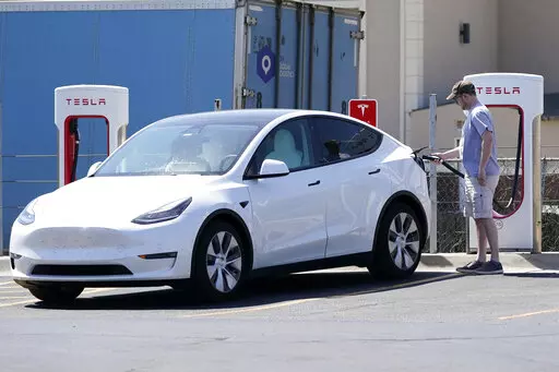 A Tesla owner charges his vehicle at a charging station in Topeka, Kan., Monday, April 5, 2021.  Tesla reported 273 crashes involving partially automated driving systems, according to statistics released by U.S. safety regulators on Wednesday, June 15, 2022. But the National Highway Traffic Safety Administration cautioned against using the numbers to compare automakers, saying it didn’t weigh them by the number of vehicles from each manufacturer that use the systems, or how many miles those ve
