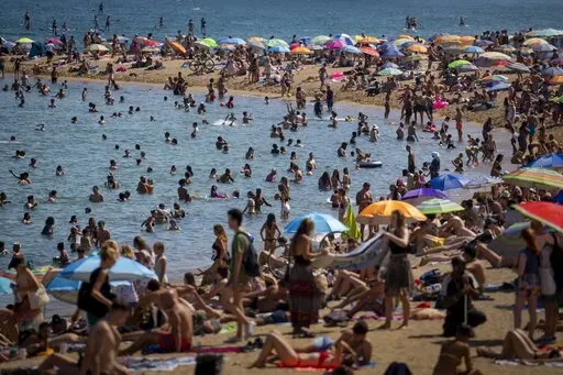 People cool off in the water on a hot and sunny day at the beach in Barcelona, Spain, July 15, 2022. Earth’s fever persisted last year, not quite spiking to a record high but still in the top five or six warmest on record, government agencies reported Thursday, Jan. 12, 2023. (AP Photo/Emilio Morenatti, File)