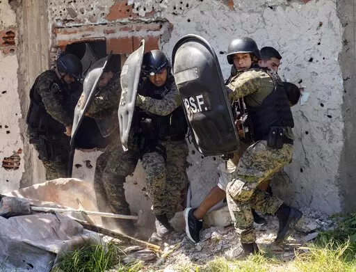 Police in riot gear protect a man neighbors accused of selling drugs, after the burial of Máximo Jerez, an 11-year-old boy killed in the crossfire of a drive-by shooting in the Los Pumitas neighborhood of Rosario, Argentina, Monday, March 6, 2023. (AP Photo/Rodrigo Abd)