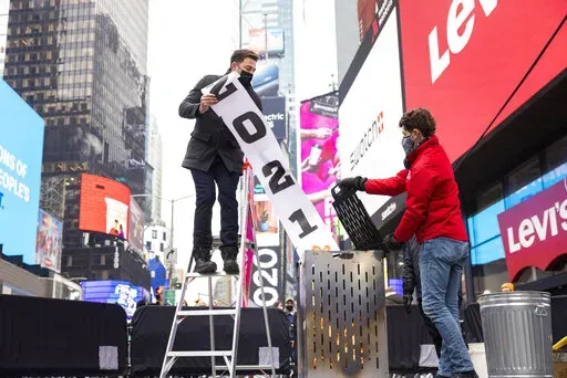 Jonathan Bennett, host of Good Riddance Day, left, and Joe Papa, Director of Events, Times Square Alliance burn a 2021 banner at the official Good Riddance Day celebration in Times Square, Tuesday, Dec. 28, 2021, in New York. (AP Photo/Corey Sipkin)