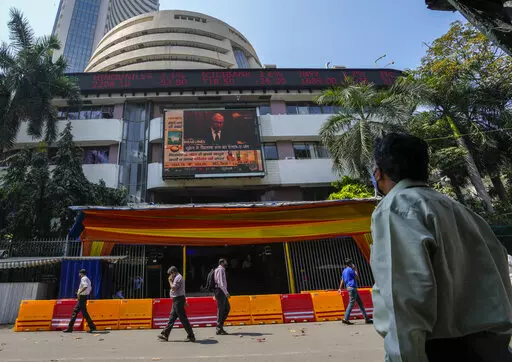 A man watches a screen showing a news item featuring Russian President Vladimir Putin on the facade of the Bombay Stock Exchange (BSE) building in Mumbai, India, Thursday, Feb. 24, 2022. Just what a vulnerable world economy didn’t need — a conflict that accelerates inflation, rattles markets and portends trouble for everyone from European consumers to indebted Chinese developers and families in Africa that are enduring soaring food prices. Russia’s attack on Ukraine and retaliatory sanctio