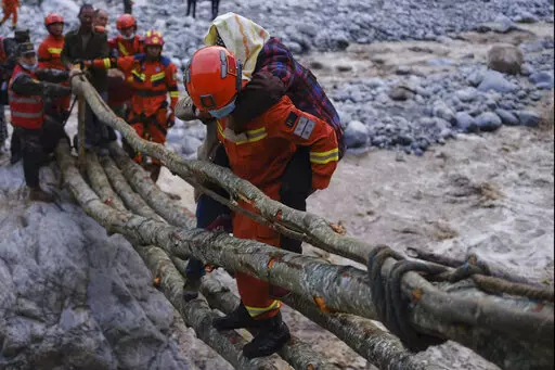 In this photo released by Xinhua News Agency, rescuers carry a villager across a river following an earthquake in Moxi Town of Luding County, southwest China's Sichuan Province on Monday, Sept. 5, 2022. Dozens people were reported killed and missing in a 6.8 magnitude earthquake that shook China's southwestern province of Sichuan on Monday, triggering landslides and shaking buildings in the provincial capital of Chengdu, whose 21 million residents are already under a COVID-19 lockdown. (Cheng Xu