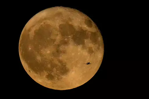 A commercial airliner flies Northwest across Lake Michigan in front of the "Full Buck" supermoon, the first of four supermoons in 2023, July 3, 2023, in Chicago. The cosmos is offering up a double feature in August: a pair of supermoons. Catch the first show Tuesday night, Aug. 2, as the full moon rises in the southeast. (AP Photo/Charles Rex Arbogast, File)