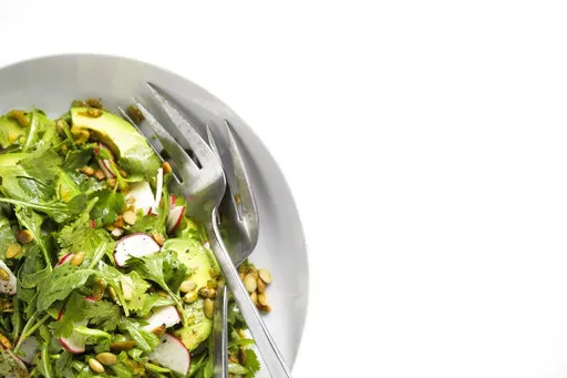 This image released by Milk Street shows a recipe for Arugula and Avocado Salad with Jalapeño Vinaigrette. (Milk Street via AP)