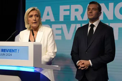 French far-right leader Marine Le Pen speaks as Jordan Bardella, president of the French far-right National Rally, listens at the party election night headquarters after French President Emanuel Macron announced he dissolves National Assembly and calls new legislative election after defeat in EU vote, Sunday, June 9, 2024 in Paris. First projected results from France put far-right National Rally party well ahead in EU elections, according to French opinion poll institutes. (AP Photo/Lewis Joly)