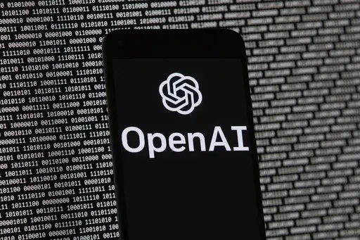 The OpenAI logo appears on a mobile phone in front of a computer screen with random binary data, March 9, 2023, in Boston. (AP Photo/Michael Dwyer, File)