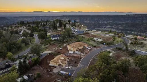 The sun sets over Valley Ridge Drive, Thursday, Oct. 26, 2023, in Paradise, Calif. Empty lots, homes under construction and residences built after the Camp Fire line the street. (AP Photo/Noah Berger)