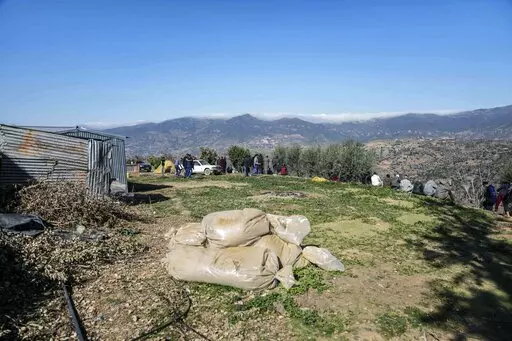 Bags of harvested cannabis left to dry in the sun as mourners gather around a hill at the funeral of five year old Rayan after his body was retrieved from a deep well, in the village of Ighran in Morocco's Chefchaouen province, Monday, Feb. 7, 2022. The death of a 5-year-old boy trapped for days in the dark depths of a well symbolizes for many villagers a curse that haunts their remote mountainous region in northern Morocco. Rif is dirt poor, neglected and dependent on its illegal cannabis crop 