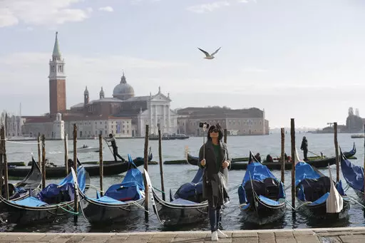 A tourist takes a selfie in St. Mark's Square in Venice, Italy, Nov. 12, 2016. Starting in January, Venice will oblige day-trippers to make reservations and pay a fee to visit the historic lagoon city. On many days, the heart of Venice is overwhelmed by visitors, who often far outnumber residents. Venice officials on Friday unveiled new rules for day-trippers, which go into effect on Jan. 16, 2023. (AP Photo/Luca Bruno, File)