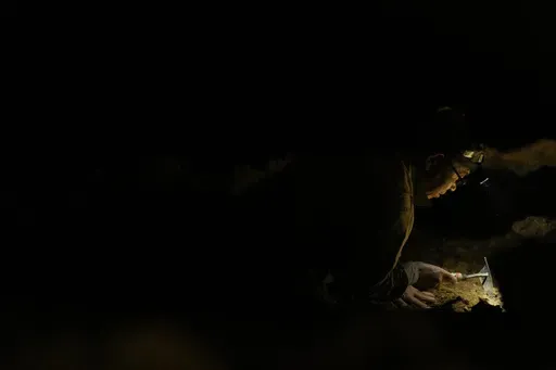 Takamatsu Gushiken uses a hand hoe to delicately move dirt in a cave while searching for the remains of those who died during the Battle of Okinawa towards the end of the World War II in 1945, in Itoman, on the main island of the Okinawa archipelago, southern Japan, Saturday, Feb. 15, 2025. (AP Photo/Hiro Komae)