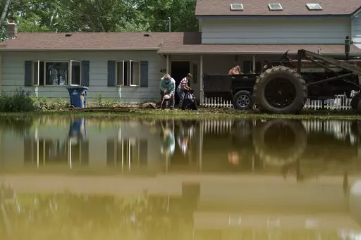 Aileen Rogers, right, and Melody Murter help clean out a friend's house badly damaged by the severe flooding in Fromberg, Mont., Friday, June 17, 2022. (AP Photo/David Goldman)