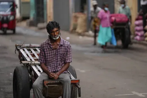 A daily wage laborer waits for work at a wholesale market in Colombo, Sri Lanka, Sunday, June 26, 2022. Sri Lankans have endured months of shortages of food, fuel and other necessities due to the country's dwindling foreign exchange reserves and mounting debt, worsened by the pandemic and other longer term troubles. (AP Photo/Eranga Jayawardena)