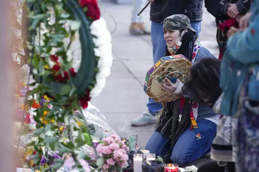 Mourners gather outside the door of a tattoo parlor along South Broadway Tuesday, Dec. 28, 2021, in Denver, one of the scenes of a shooting spree that left multiple people dead—including the suspected shooter Monday evening—and a few more people wounded. The spree spread from the core of Denver to the western suburb of Lakewood where the suspect was shot and killed by police near a busy intersection in a bustling shopping district. (AP Photo/David Zalubowski)