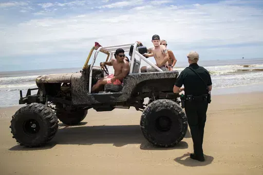 A group of people riding in a Jeep during the Go Topless Jeep Weekend event get stopped by a Galveston County Sheriff's Office deputy at Crystal Beach on Bolivar Peninsula, Texas, May 17, 2020. (Marie D. De Jesús/Houston Chronicle via AP, File)